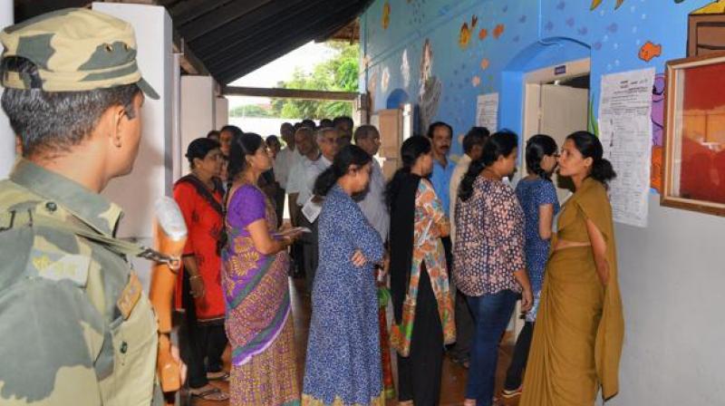 Voters stand in a queue to cast their votes