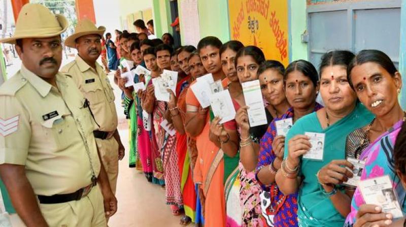 Voters stand in queue outside a polling booth during the Karnataka elections 2018