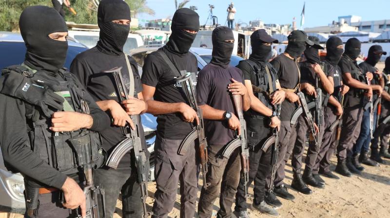Palestinian militants stand guard as the hostages were being handed over to International Committee of the Red Cross in Khan Younis (Courtesy: The Reuters)