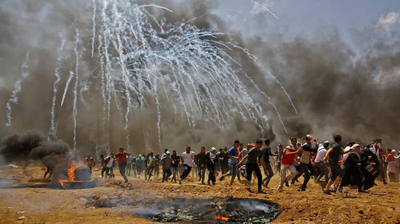 Palestinians run for cover from tear gas during clashes with Israeli security forces