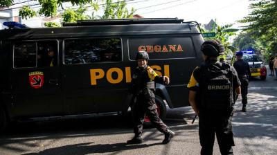 Indonesian policemen patrol outside a church following a suicide bomb