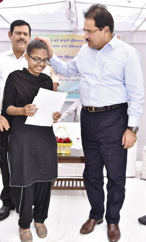 O.P Soni presenting cash award and commendation certificate to meritorious student of PSEB 2018 Exams