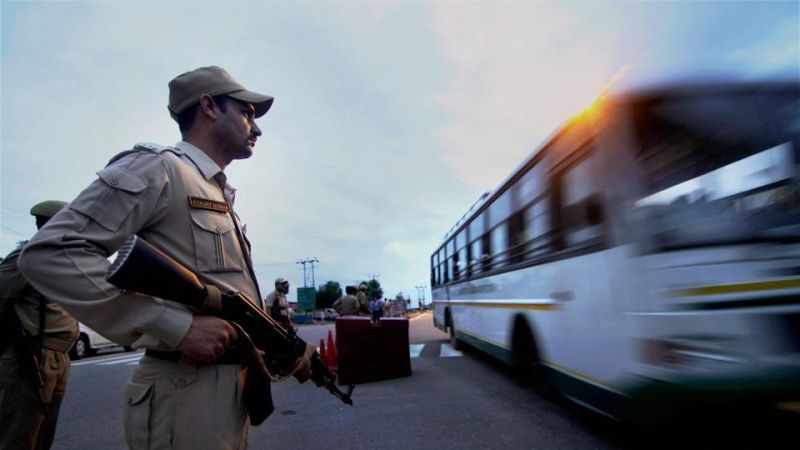A security person stands guard as pilgrims leave for the Amarnath Yatra