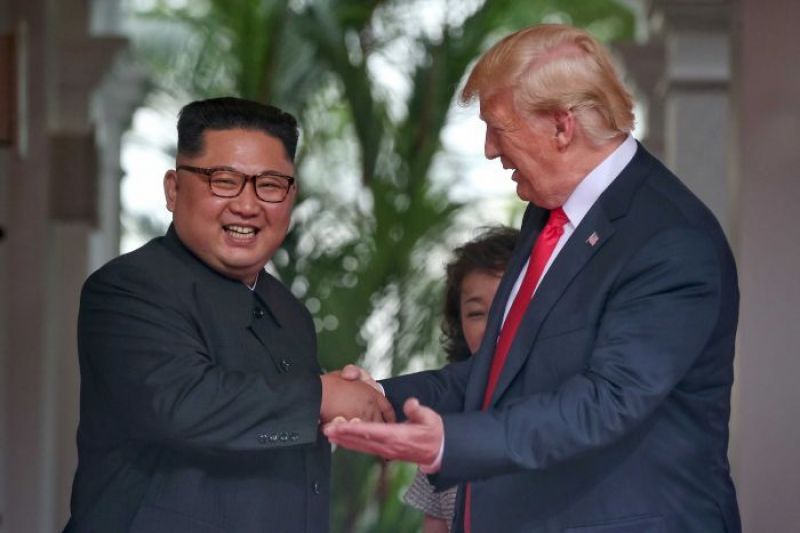 Donald Trump gestures as he talks to smiling Kim Jong-un