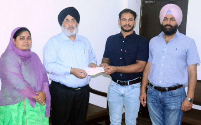 Daljit Singh Cheema handing over a cheque to the wrestler on the behalf of the SAD president